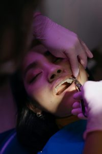 Home Patient undergoing a dental procedure with focus on examination tools and healthcare setting.